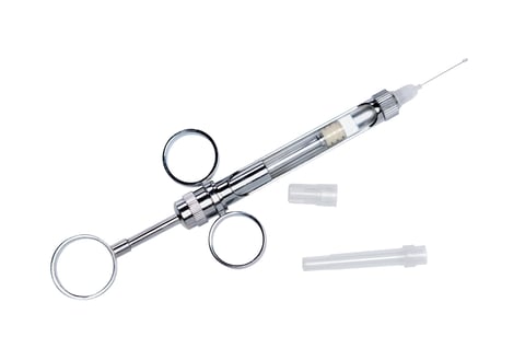 Syringe for anesthesia in dentistry with a used capsule for the needle, close-up top view isolated on white background