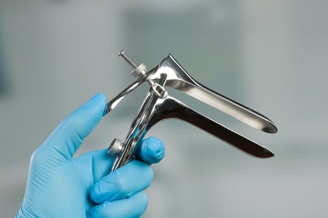hand in blue gloves and a speculum