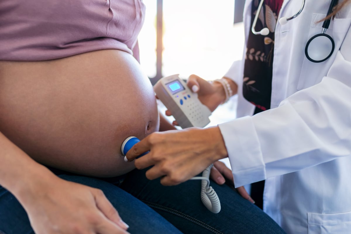 Close-up of obstetrician gynecologist performing Doppler auscultation checking blood flow in placenta and uterus in the clinic.