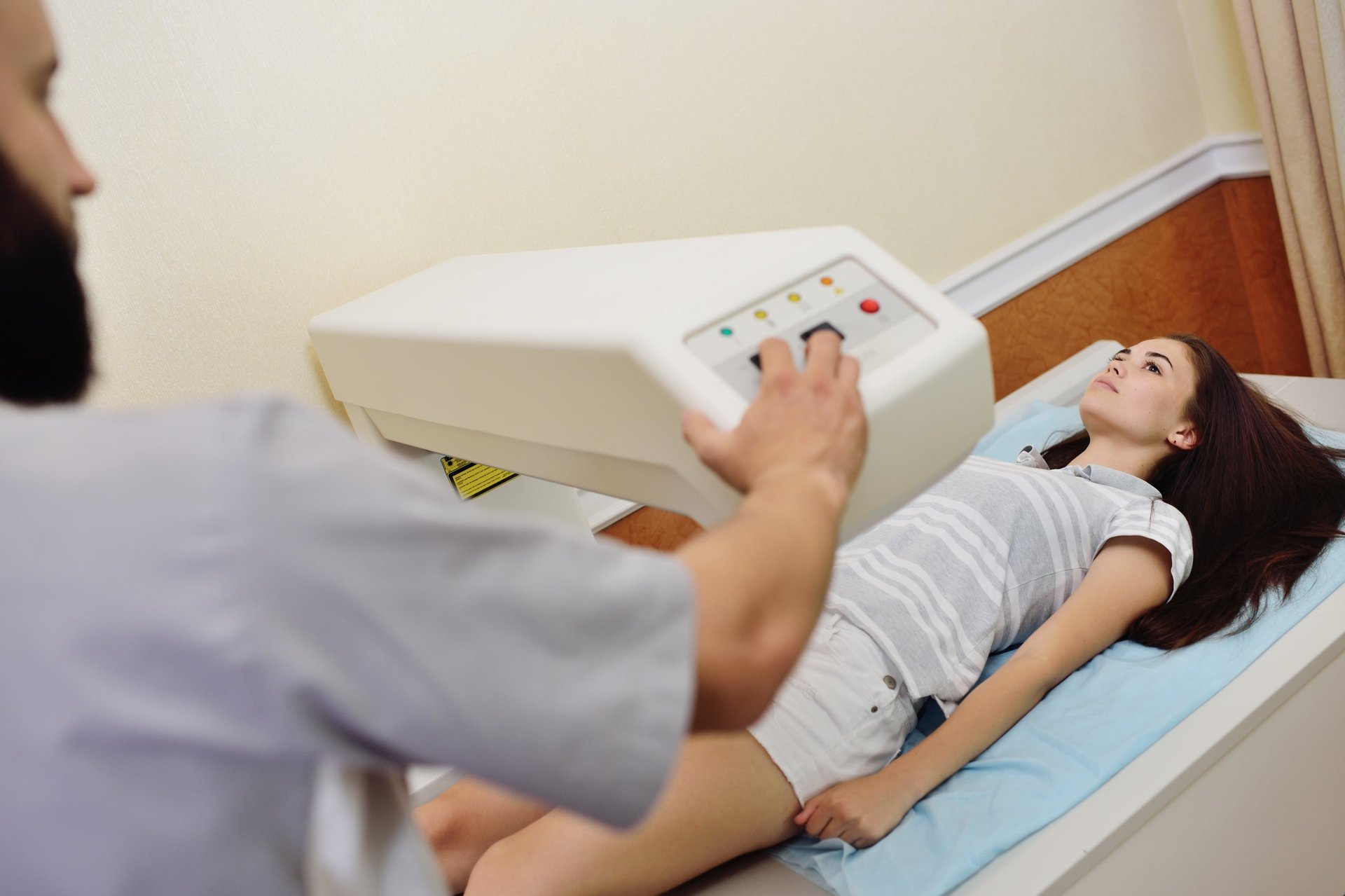 The doctor examines a young woman on a bone densitometer