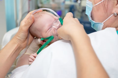 Baby with an oxygen mask in the neonatal unit