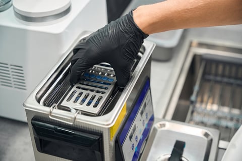 Close-up view dental technician putting down the tray with dental nozzles into ultrasonic bath for cleaning and reprocessing of dental instruments