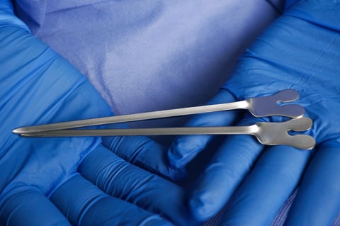Doctor wearing blue medical gloves holding grooved director