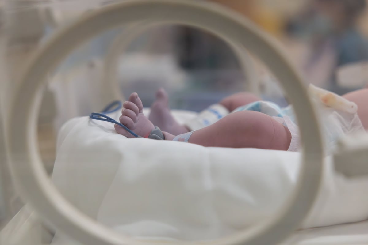 A baby's feet are visible in a hospital incubator