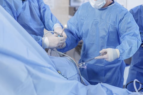 Surgeons performing knee arthroscopy with ligament reconstruction using arthroscope and instruments in sterile operating room