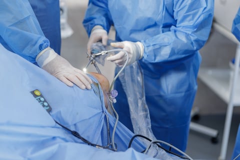 Close view of knee arthroscopy with PCL reconstruction showing arthroscope and portals on blue sterile drapes
