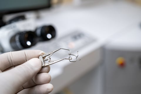 A close-up view of an adjustable wire-frame eyelid speculum surgical tool