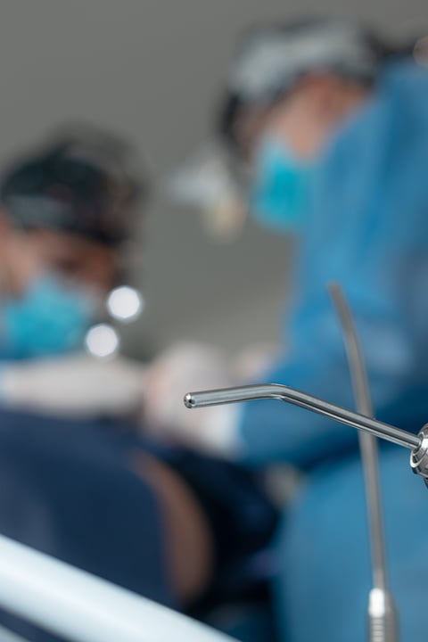 Artistic selective focus shot of a metal surgical suction cannula or instrument in the foreground