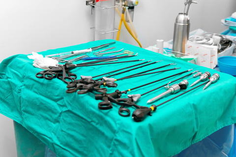 Sterile surgical instruments and tools including scalpels, scissors, forceps and tweezers arranged on a table preparation for surgery