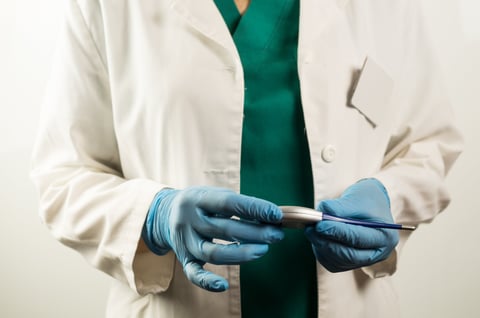 Hands of a medical professional in protective gloves holding a digital thermometer