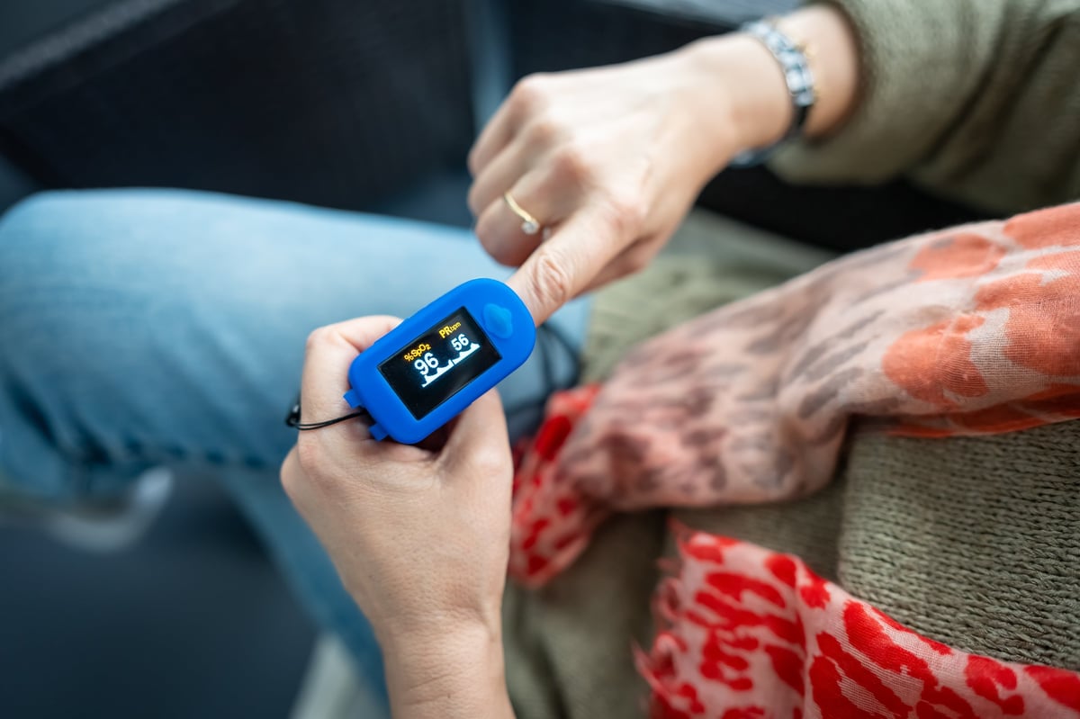 Woman resting at home using pulse oximeter