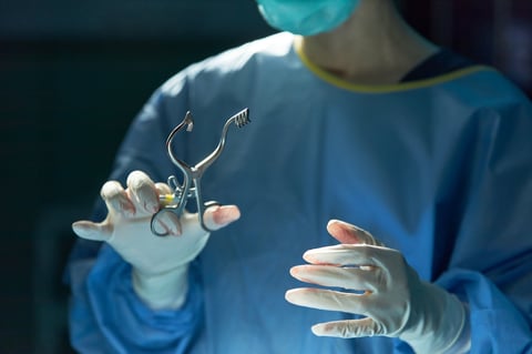 Close up of surgeon holding surgical retractor during operation, showing sterile medical procedure and precision