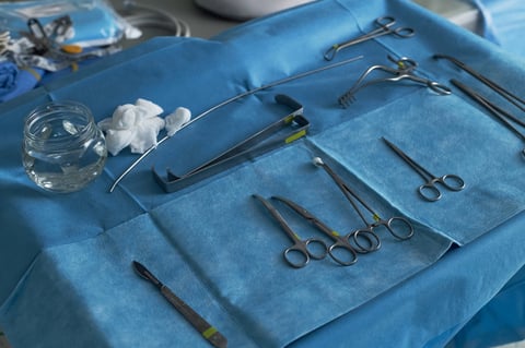 Close up of surgical instruments arranged on sterile drape, preparing operating room workflow