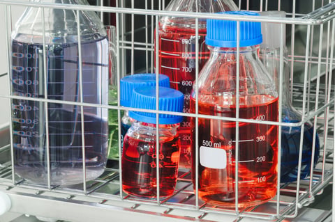 Glass bottles with multi-colored solutions in basket in chemical biology laboratory