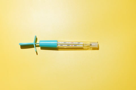 Mercury thermometer on a yellow background with strong sunlight shadow