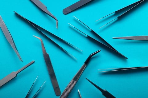 Top view of a group of metal tweezers on a blue-green table