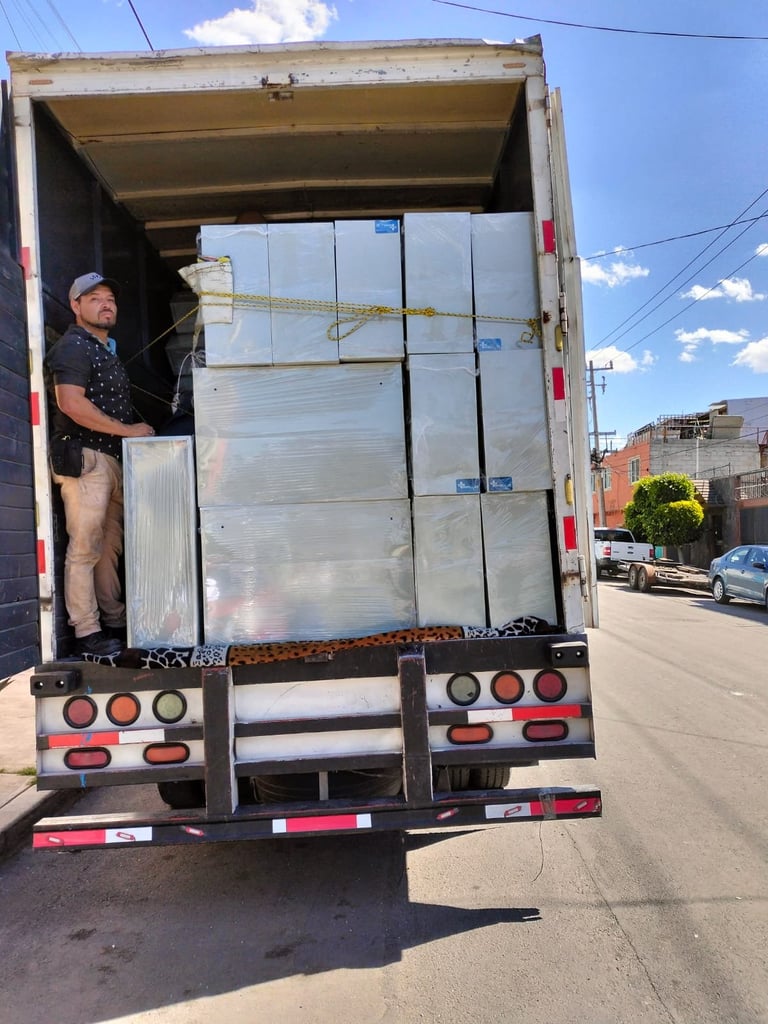 Delivery truck open with a worker standing inside among stacked plastic storage containers on a residential street