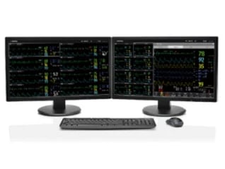 Dual monitor computer workstation displaying system analytics and data charts with keyboard and mouse