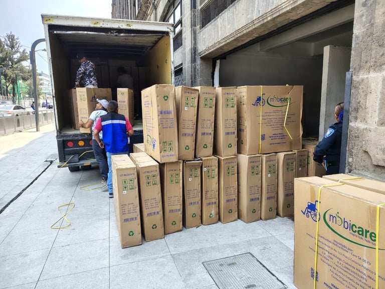 Workers unloading cardboard boxes from a delivery truck parked on a city street outside a building