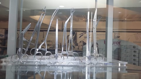 Display of multiple chrome dental instruments and tools arranged on a glass shelf in a clinical or retail setting