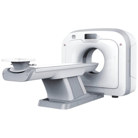 White and gray CT scanner medical imaging machine with patient table extended from the circular gantry opening