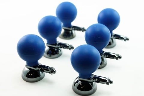 Six blue dome-shaped joystick controllers with gray bases arranged on a white surface