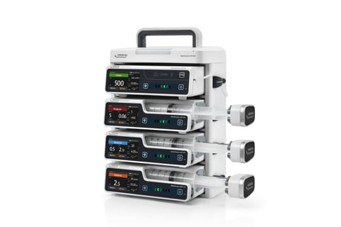 Stack of four medical infusion pumps with digital displays and injection ports, featuring a carrying handle on top