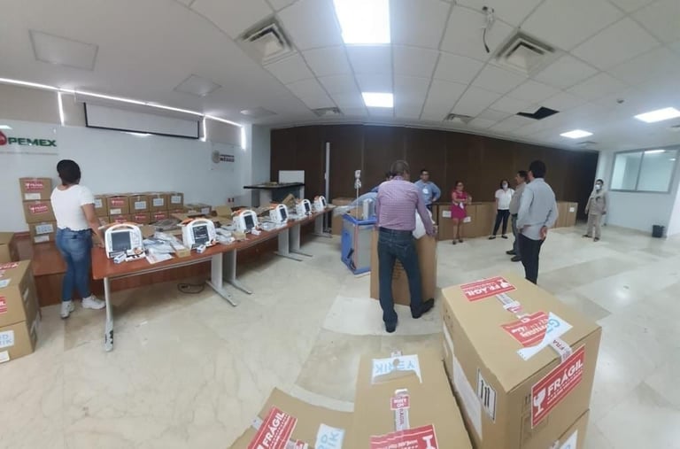 Community event or volunteer day in a large indoor space with cardboard boxes, tables, and people organizing supplies or donations
