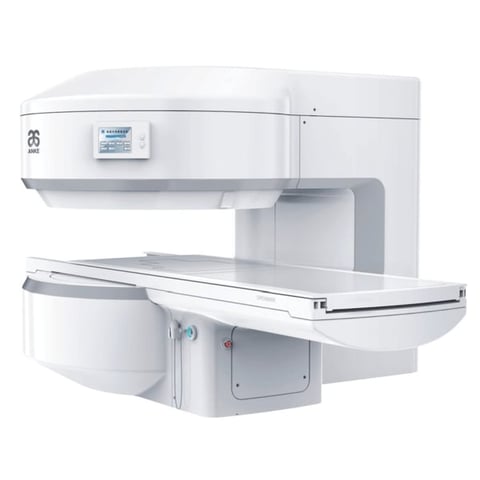 White medical imaging machine, likely an MRI or CT scanner, with an open patient table and control panel