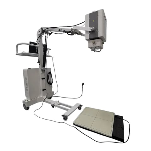 Medical imaging equipment with X-ray tube arm on mobile cart and detector pad positioned on examination table